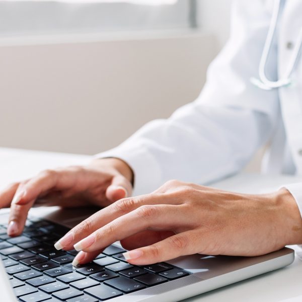Vertical shot of unrecognizable doctor working on laptop at medical office